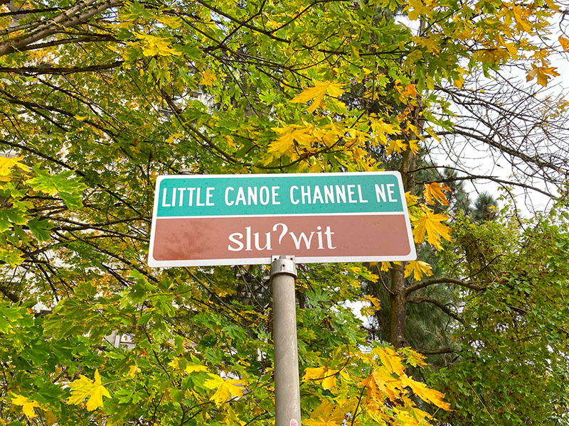 Street sign on the University of Washington campus reading Little Canoe Channel NE / sluʔwit; ‘t’ appears instead of the correct ‘ɫ’. sluʔwiɫ means ‘little canoe channel’ in Lushootseed. October 27, 2021