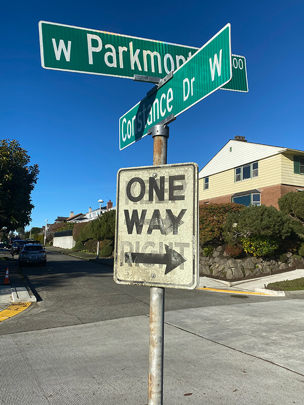 W Parkmont Drive and Constance Drive W street sign above One Way sign with Keep Right ghost sign underneath